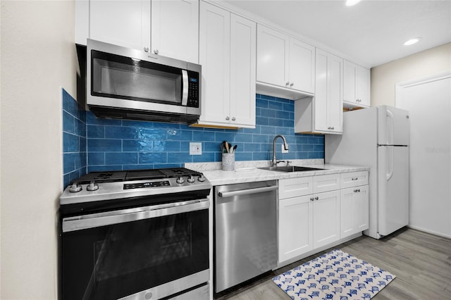 1700 SW 16th Ct Unit E9, Gainesville, FL 32608 - kitchen featuring appliances with stainless steel finishes, backsplash, white cabinets, and recessed lighting