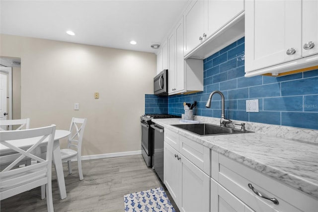 1700 SW 16th Ct Unit E9, Gainesville, FL 32608 - kitchen featuring stainless steel appliances, white cabinets, backsplash, light wood finished floors, and recessed lighting