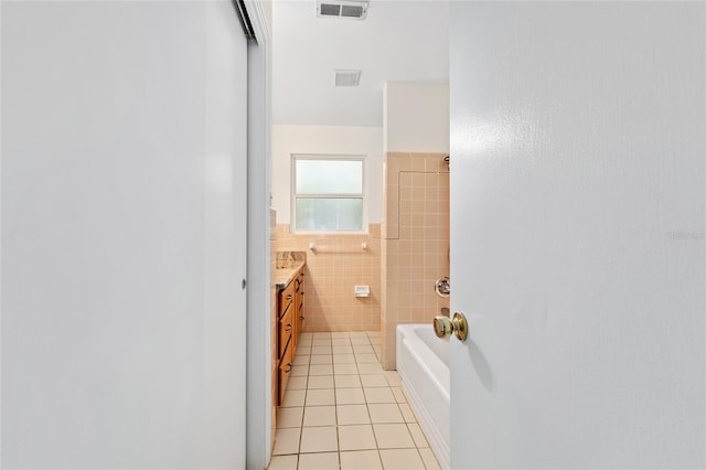 3857 SW 4th Pl, Gainesville, FL 32607 - bathroom with tile walls, tile patterned floors, vanity, a wainscoted wall, and tub / shower combination