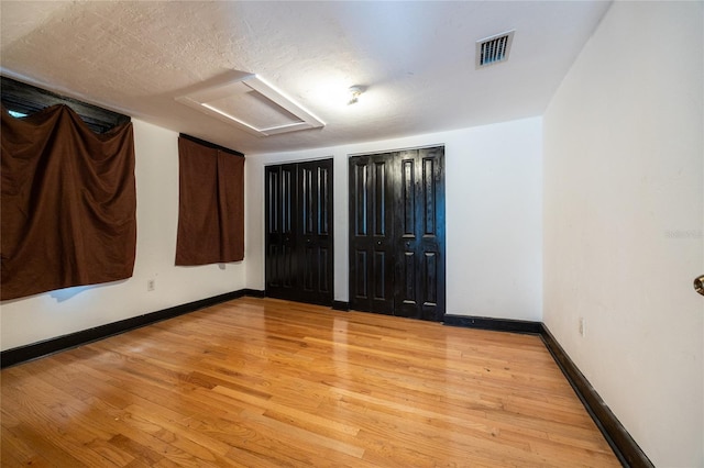 407 NW 8th St, Gainesville, FL 32601 - unfurnished bedroom with attic access, light wood finished floors, and multiple closets