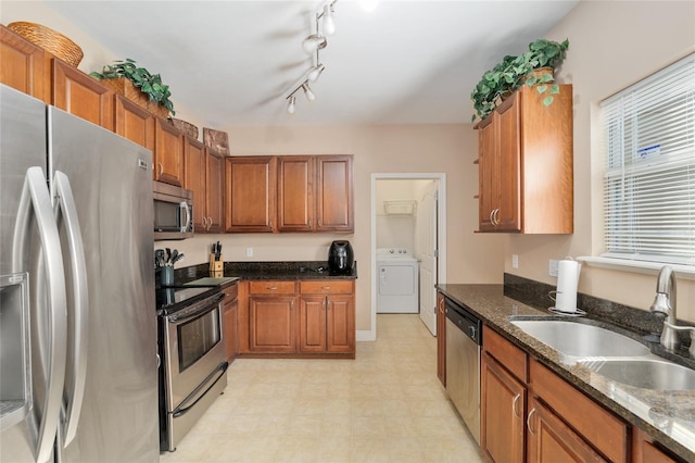 7547 SW 87th Ter, Gainesville, FL 32608 - kitchen featuring appliances with stainless steel finishes, washer / dryer, brown cabinetry, light floors, and dark stone countertops