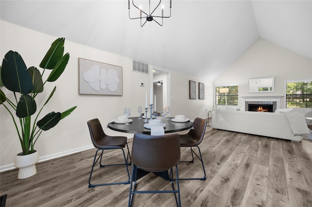 2101 SW 79th Dr, Gainesville, FL 32607 - dining area featuring vaulted ceiling, wood finished floors, a tile fireplace, and a chandelier