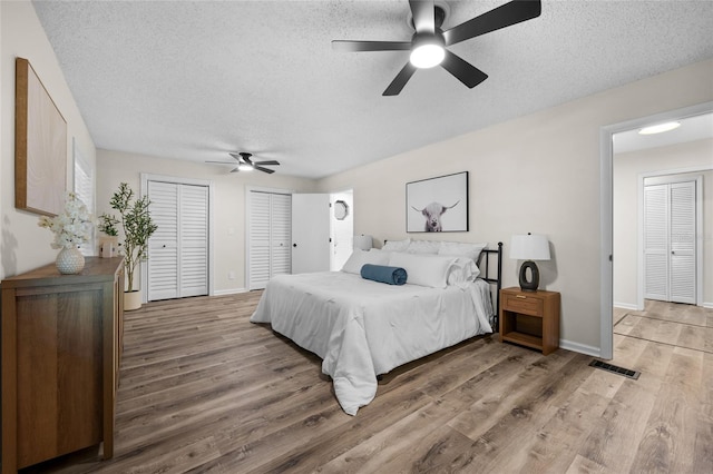 2101 SW 79th Dr, Gainesville, FL 32607 - bedroom with a textured ceiling, light wood-style flooring, two closets, and a ceiling fan