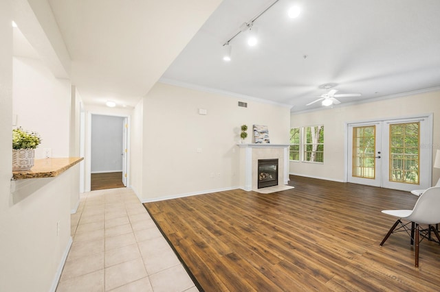 5133 SW 91st Ct Unit G202, Gainesville, FL 32608 - unfurnished living room featuring track lighting, wood finished floors, a tile fireplace, ceiling fan, and ornamental molding