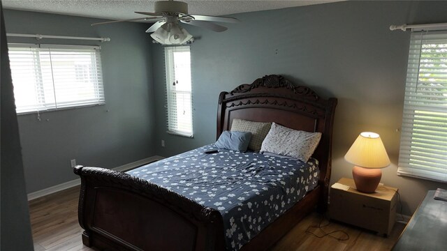 32932 Crooked Oaks Ln, Leesburg, FL 34748 - bedroom with multiple windows, wood finished floors, a ceiling fan, and a textured ceiling