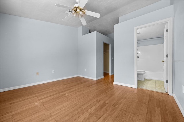 4415 SW 34th St Unit 107, Gainesville, FL 32608 - unfurnished bedroom with light wood-style flooring, a spacious closet, a closet, ensuite bath, and a ceiling fan