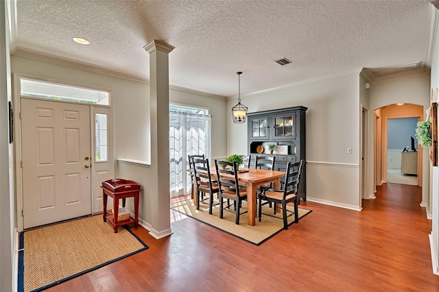 6618 SW 83rd Ter, Gainesville, FL 32608 - dining room with light wood-style flooring, ornamental molding, a textured ceiling, arched walkways, and decorative columns