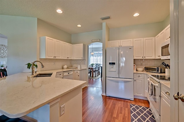 6618 SW 83rd Ter, Gainesville, FL 32608 - kitchen featuring white appliances, a peninsula, tasteful backsplash, arched walkways, and recessed lighting
