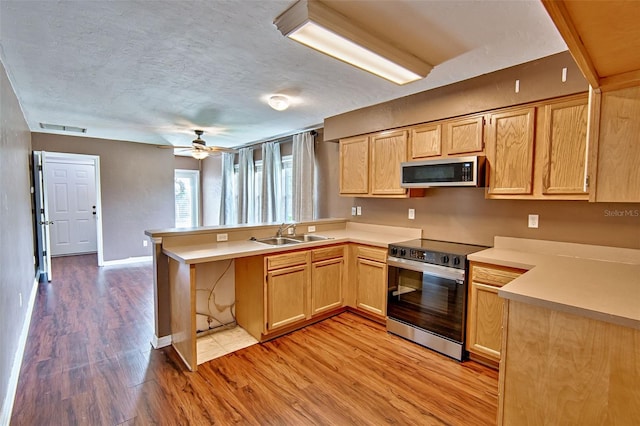 3701 NW 26th St, Gainesville, FL 32605 - kitchen with appliances with stainless steel finishes, a peninsula, light wood-style floors, light countertops, and a textured ceiling