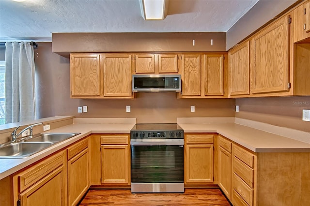 3701 NW 26th St, Gainesville, FL 32605 - kitchen featuring appliances with stainless steel finishes, light wood finished floors, light countertops, and a textured ceiling