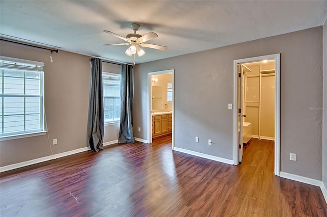 3701 NW 26th St, Gainesville, FL 32605 - unfurnished bedroom with multiple windows, dark wood finished floors, a walk in closet, and connected bathroom