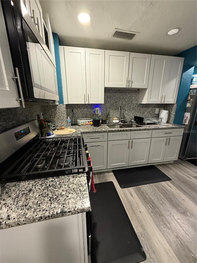 1510 SE 14th Ave, Gainesville, FL 32641 - kitchen featuring appliances with stainless steel finishes, backsplash, light wood-type flooring, white cabinetry, and recessed lighting
