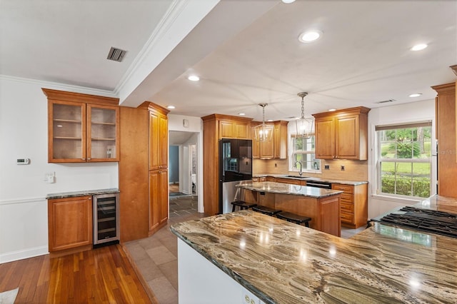 2506 SW 9th Dr, Gainesville, FL 32601 - kitchen featuring light stone countertops, brown cabinets, freestanding refrigerator, a kitchen island, and beverage cooler