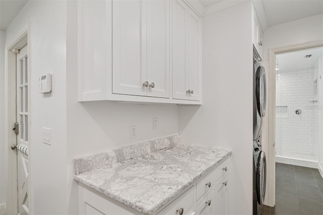2506 SW 9th Dr, Gainesville, FL 32601 - kitchen with stacked washer / drying machine, white cabinetry, light stone counters, and dark tile patterned floors