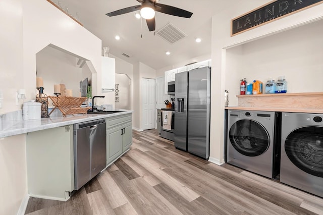 3292 NE 42nd Pl, Ocala, FL 34479 - kitchen featuring appliances with stainless steel finishes, washing machine and dryer, ceiling fan, light wood-type flooring, and vaulted ceiling