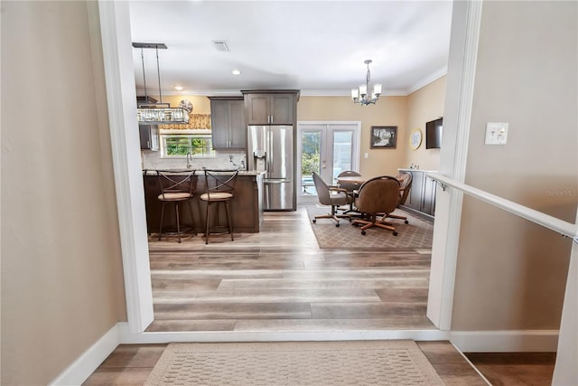 174 SW Dalmation Ln, Lake City, FL 32024 - kitchen featuring stainless steel fridge with ice dispenser, a chandelier, crown molding, a kitchen bar, and hanging light fixtures