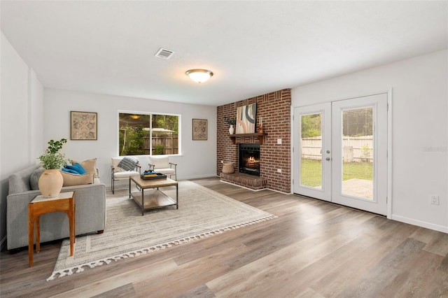 1604 NE 7th St, Gainesville, FL 32609 - living room with plenty of natural light, wood finished floors, french doors, and a brick fireplace