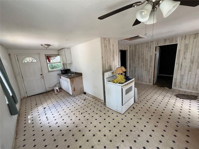 654 NE 2nd St, Crystal River, FL 34429 - kitchen featuring electric range, wood walls, a ceiling fan, white cabinets, and dark countertops