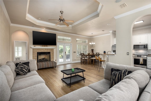 3737 SW 74th Dr, Gainesville, FL 32608 - living room with a tray ceiling, ceiling fan, light wood-style flooring, crown molding, and a chandelier