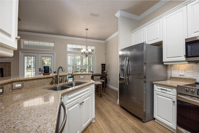 3737 SW 74th Dr, Gainesville, FL 32608 - kitchen with appliances with stainless steel finishes, ornamental molding, light wood finished floors, a chandelier, and white cabinets