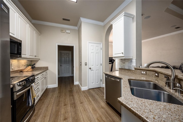 3737 SW 74th Dr, Gainesville, FL 32608 - kitchen featuring appliances with stainless steel finishes, light stone counters, white cabinets, arched walkways, and ornamental molding