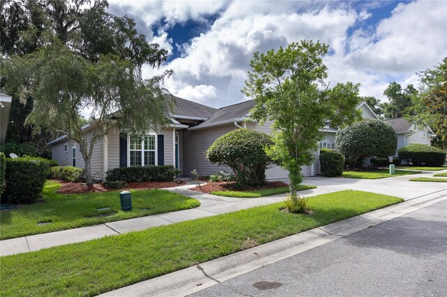 3737 SW 74th Dr, Gainesville, FL 32608 - view of property hidden behind natural elements with driveway, a front lawn, and an attached garage