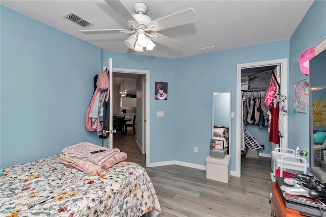 8198 N Brook Way, Citrus Springs, FL 34433 - bedroom with a walk in closet, wood finished floors, a closet, a ceiling fan, and a textured ceiling