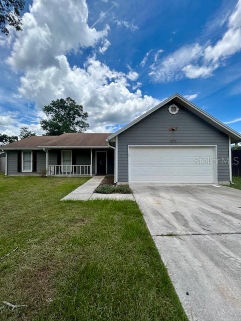 3372 Penny Ln, Middleburg, FL 32068 - ranch-style house with driveway, an attached garage, a front yard, and covered porch