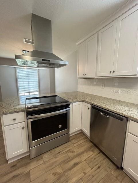 3372 Penny Ln, Middleburg, FL 32068 - kitchen featuring appliances with stainless steel finishes, range hood, light wood-type flooring, and white cabinetry