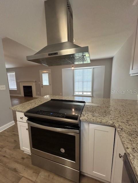 3372 Penny Ln, Middleburg, FL 32068 - kitchen featuring stainless steel electric range, exhaust hood, white cabinetry, and plenty of natural light
