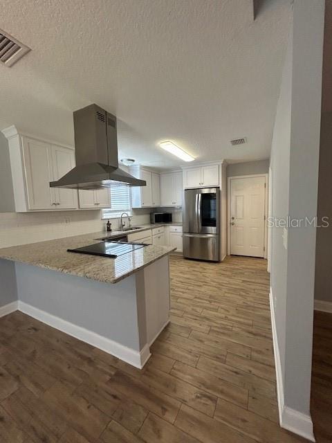 3372 Penny Ln, Middleburg, FL 32068 - kitchen featuring appliances with stainless steel finishes, island range hood, white cabinets, a peninsula, and wood finished floors