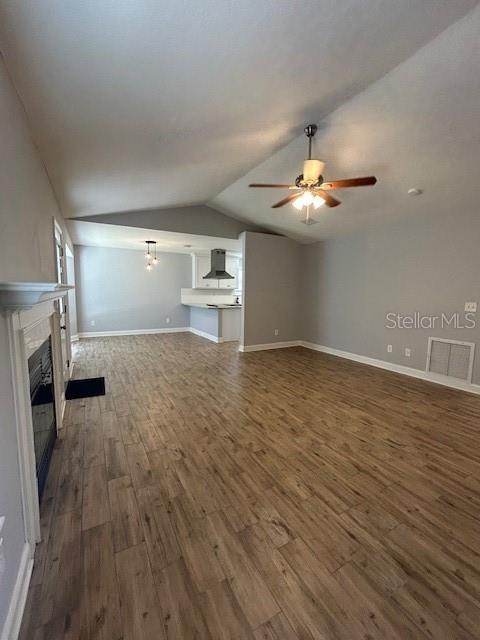 3372 Penny Ln, Middleburg, FL 32068 - unfurnished living room featuring a glass covered fireplace, dark wood-style flooring, ceiling fan, and vaulted ceiling