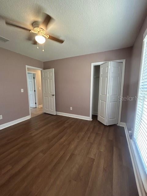 3372 Penny Ln, Middleburg, FL 32068 - unfurnished bedroom featuring dark wood-type flooring, a textured ceiling, a closet, and a ceiling fan
