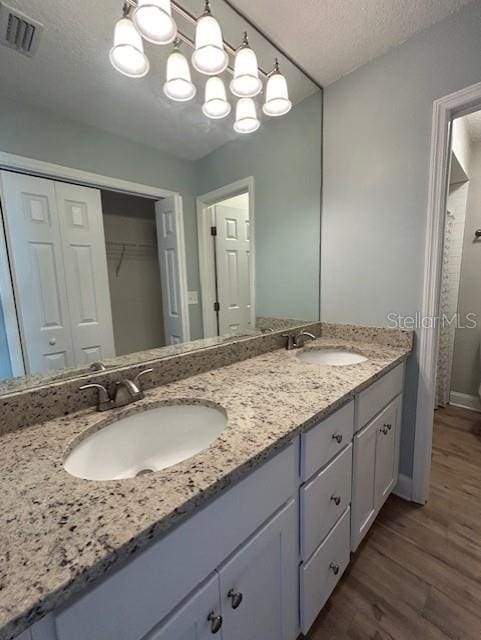 3372 Penny Ln, Middleburg, FL 32068 - bathroom with double vanity, wood finished floors, a textured ceiling, a spacious closet, and a chandelier