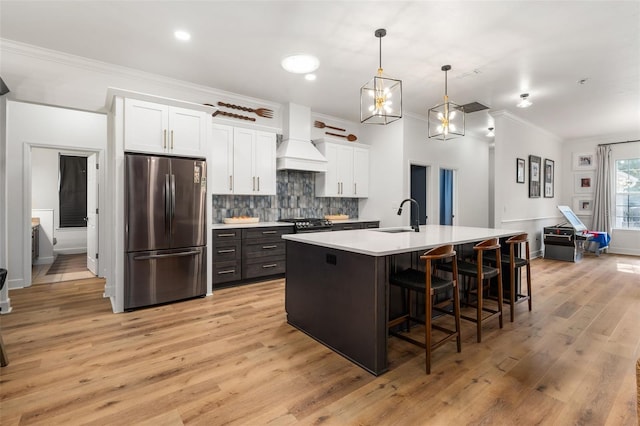 6326 SW 90th St, Gainesville, FL 32608 - kitchen featuring freestanding refrigerator, premium range hood, crown molding, white cabinets, and an island with sink