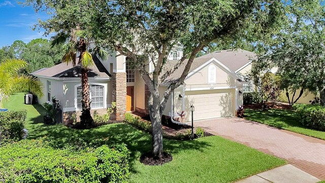 6364 Golden Eye Gln, Lakewood Ranch, FL 34202 - view of front of home featuring stucco siding, stone siding, decorative driveway, a garage, and a front lawn