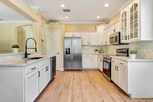 6364 Golden Eye Gln, Lakewood Ranch, FL 34202 - kitchen featuring stainless steel appliances, ornamental molding, arched walkways, glass insert cabinets, and white cabinetry