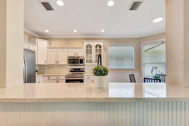 6364 Golden Eye Gln, Lakewood Ranch, FL 34202 - kitchen featuring appliances with stainless steel finishes, a peninsula, light stone countertops, white cabinetry, and recessed lighting