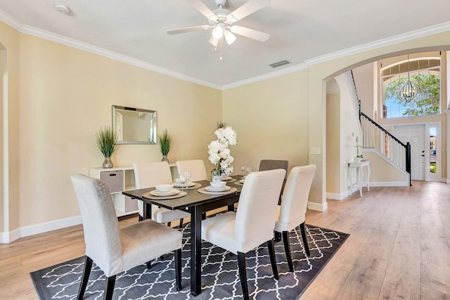 6364 Golden Eye Gln, Lakewood Ranch, FL 34202 - dining area featuring arched walkways, wood finished floors, ceiling fan, crown molding, and stairway