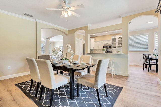 6364 Golden Eye Gln, Lakewood Ranch, FL 34202 - dining area with arched walkways, a ceiling fan, crown molding, and light wood-style flooring