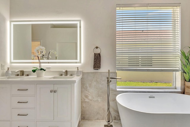 6364 Golden Eye Gln, Lakewood Ranch, FL 34202 - bathroom featuring healthy amount of natural light, a soaking tub, double vanity, and tile walls