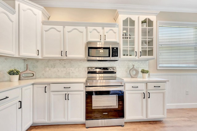 6364 Golden Eye Gln, Lakewood Ranch, FL 34202 - kitchen featuring stainless steel appliances, light wood finished floors, white cabinetry, ornamental molding, and glass insert cabinets