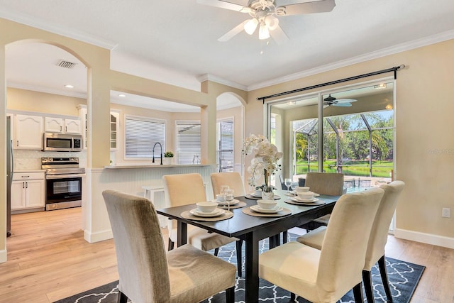 6364 Golden Eye Gln, Lakewood Ranch, FL 34202 - dining room featuring a ceiling fan, arched walkways, light wood finished floors, and ornamental molding