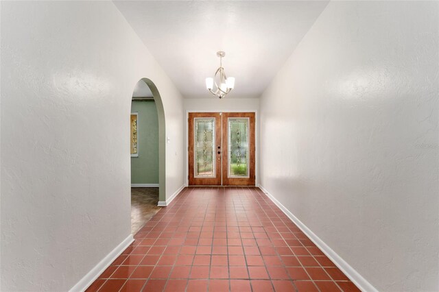 4700 NW 19th Pl, Gainesville, FL 32605 - doorway with arched walkways, a chandelier, french doors, a textured wall, and dark tile patterned floors