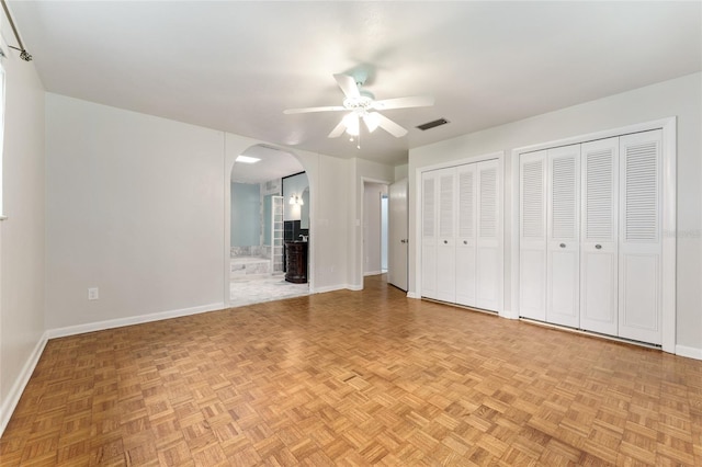 4700 NW 19th Pl, Gainesville, FL 32605 - unfurnished bedroom featuring arched walkways, multiple closets, ensuite bathroom, and a ceiling fan