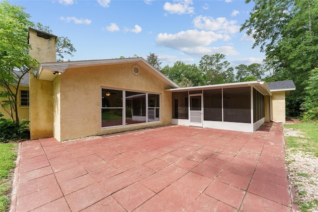 4700 NW 19th Pl, Gainesville, FL 32605 - back of house featuring stucco siding, a sunroom, a patio area, and a chimney