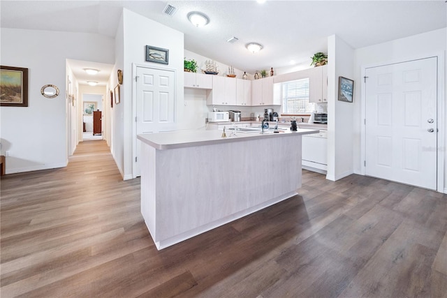 78 SE 901st Ave, Suwannee, FL 32692 - kitchen featuring vaulted ceiling, white cabinetry, light countertops, wood finished floors, and a kitchen island with sink