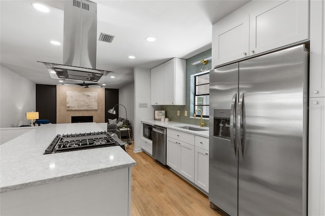 2330 NW 54th Ter, Gainesville, FL 32606 - kitchen featuring appliances with stainless steel finishes, island exhaust hood, open floor plan, white cabinetry, and light wood-style floors