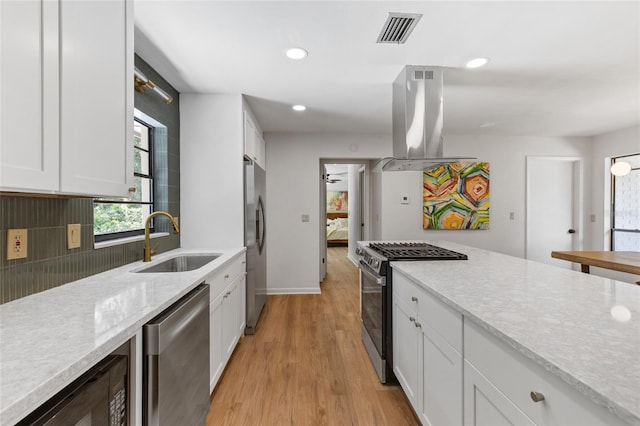 2330 NW 54th Ter, Gainesville, FL 32606 - kitchen featuring appliances with stainless steel finishes, island range hood, white cabinets, light wood finished floors, and backsplash