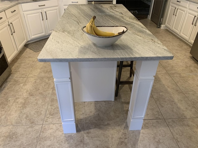 2048 Bristol Grande Way, Orlando, FL 32820 - detailed view of white cabinetry, a center island, light stone counters, and a kitchen breakfast bar